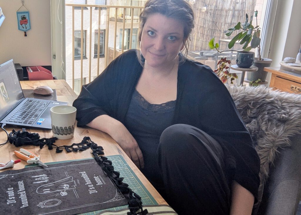 Anna is at her desk making banners.