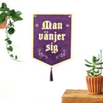 Vit vägg med lila tygbanner som har texten "Man vänjer sig".