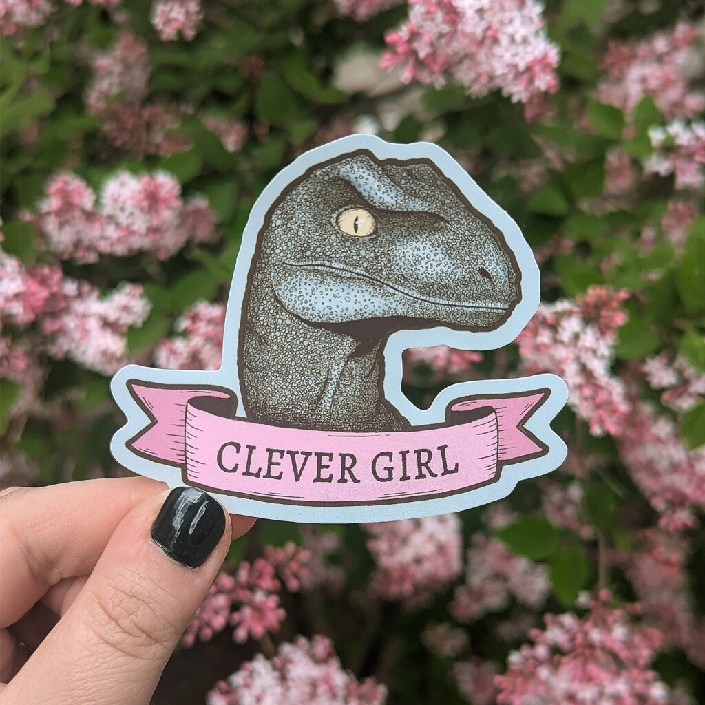 sticker with a raptor dinosaur and a pink banner with the text Clever Girl