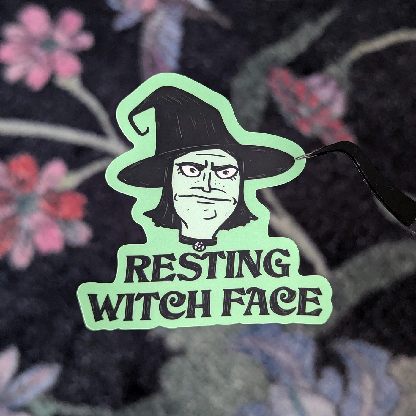 Klistermärke i grönt och svart, med en häxa och texten Resting Witch Face